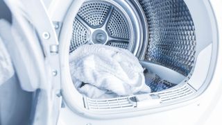 An open clothes dryer with a white towel within