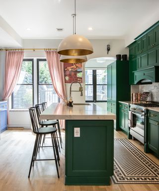 Green kitchen with matching slimline island, pink curtains, hardwood floor, pendants