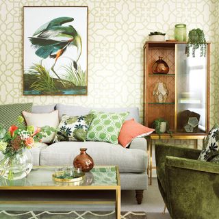 Living room with green patterned wallpaper, grey sofa, bronze edged coffee table and open storage