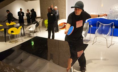 Ron Arad plays ping pong on his steel table at the Barbican.