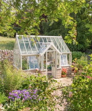greenhouse in a country garden surrounded by flowers