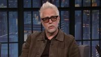 James Gunn in brown jacket talking to Seth Meyers on Late Night