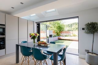 moder dining area in an open plan kitchen with bifolds leading to a modern urban garden