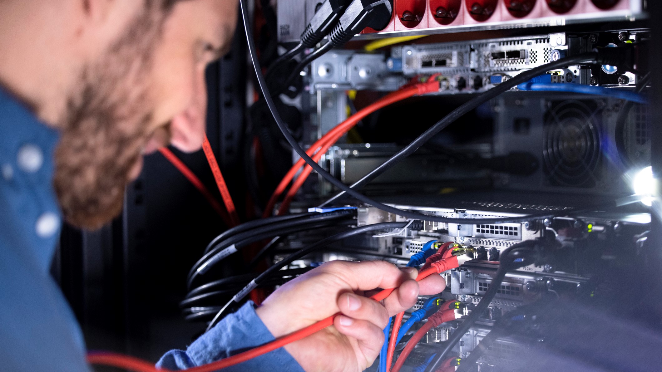 IT specialist installing patch cord cable in server rack in data center