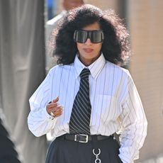 Tracee Ellis Ross wearing a striped button-down, a striped black tie, big black pants, and black loafers