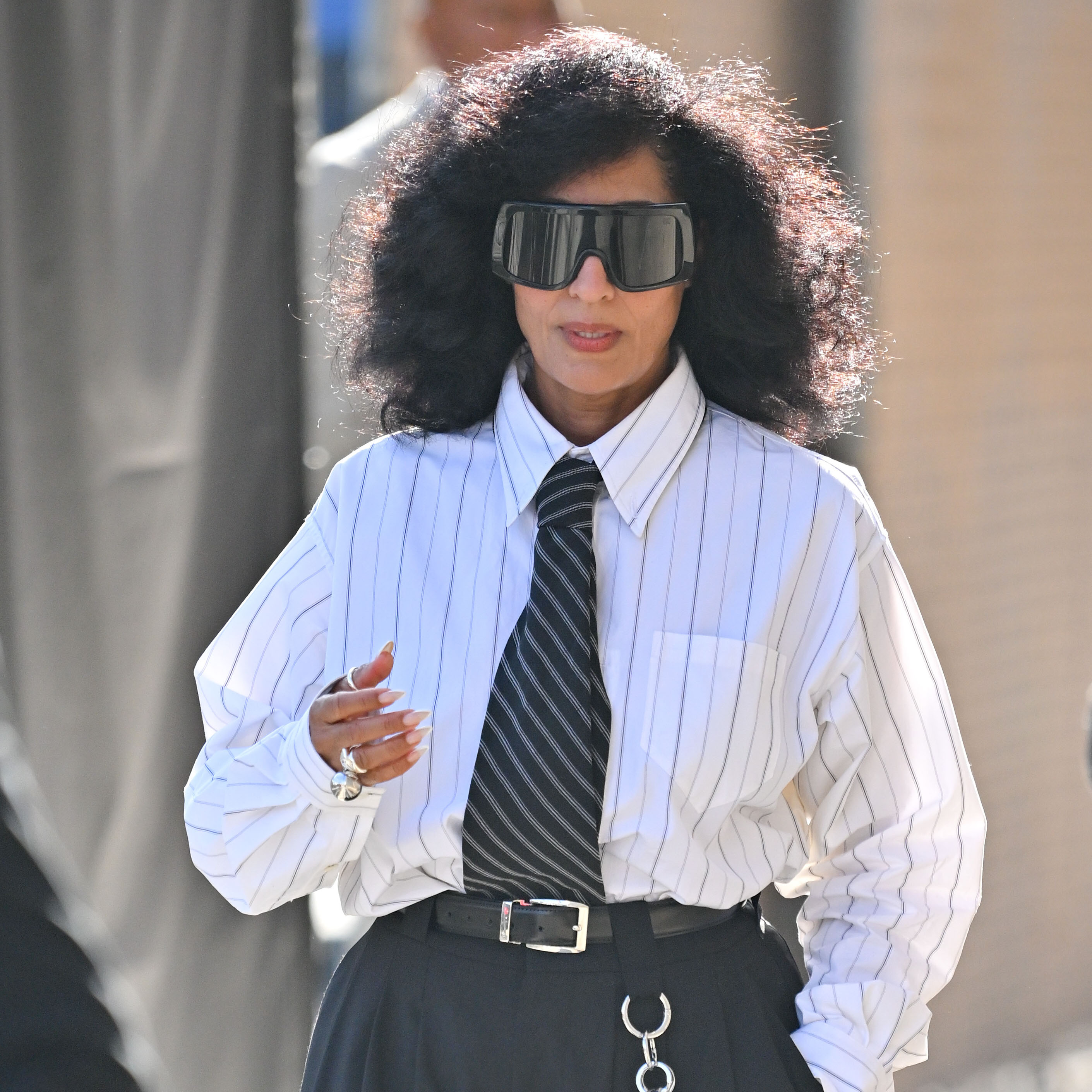 Tracee Ellis Ross wearing a striped button-down, a striped black tie, big black pants, and black loafers