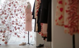 Looking along past outfits on mannequins towards a piece of artwork with a red floral design