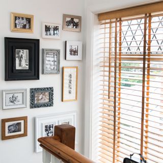 Photo frames on the wall of a stair case, with blinded windows