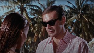Sean Connery looking down at Claudine Auger while wearing sunglasses in Thunderball.