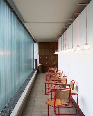 Chairs against a white wall on a corridor facing a frosted glass panel