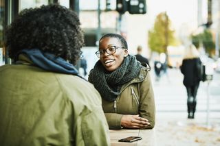 Smiling friends in discussion while sitting at outdoor cafe after work