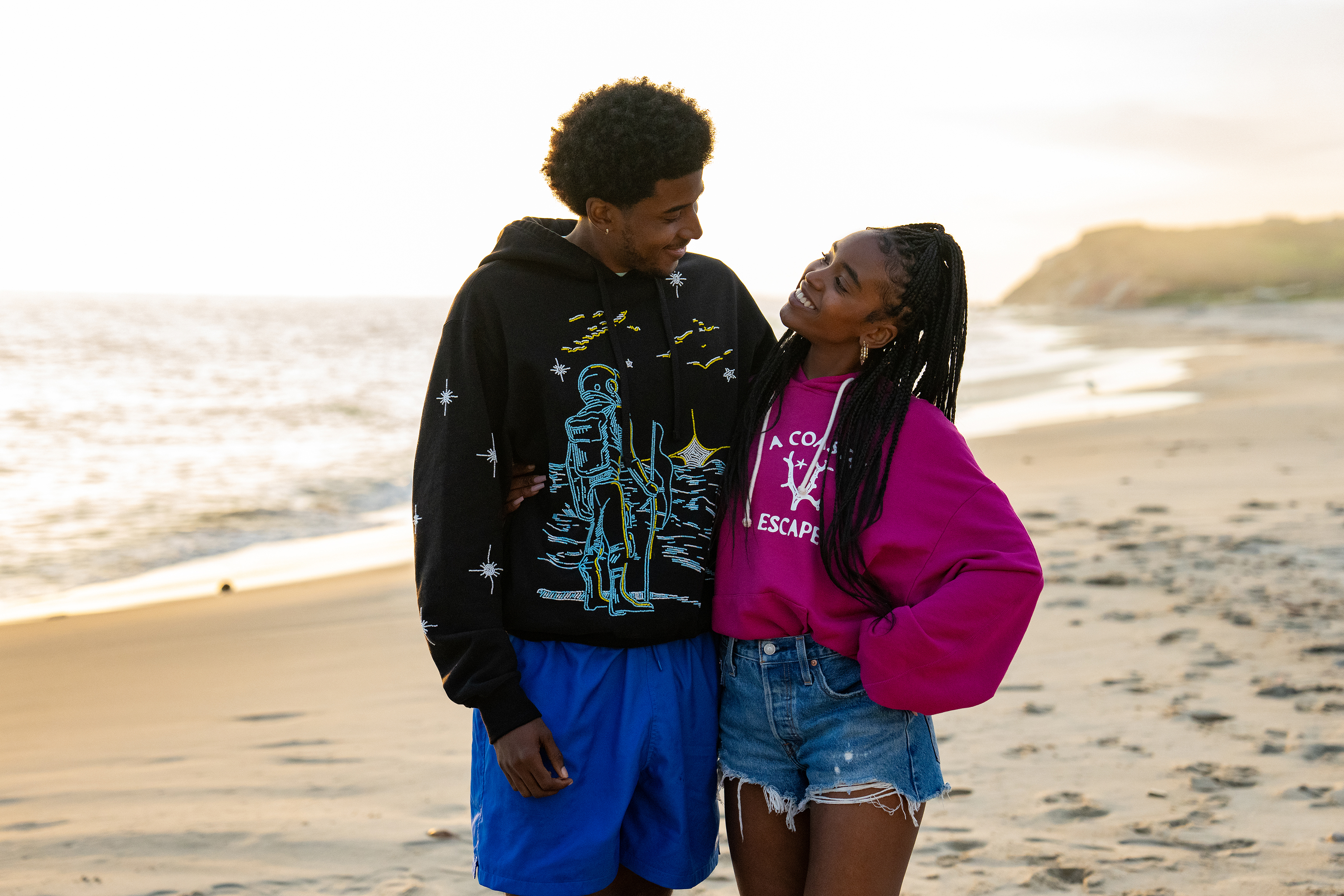 justin and keisha walk on the beach together smiling in forever