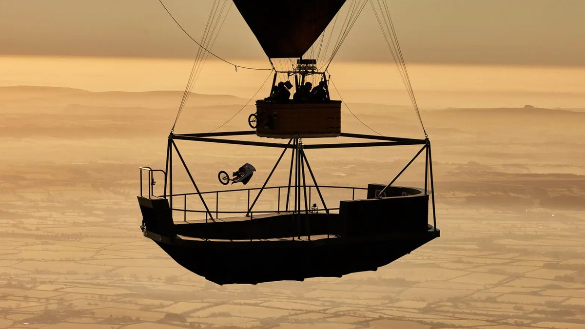 Kyle rides a BMX in a bowl suspended under a hot air balloon