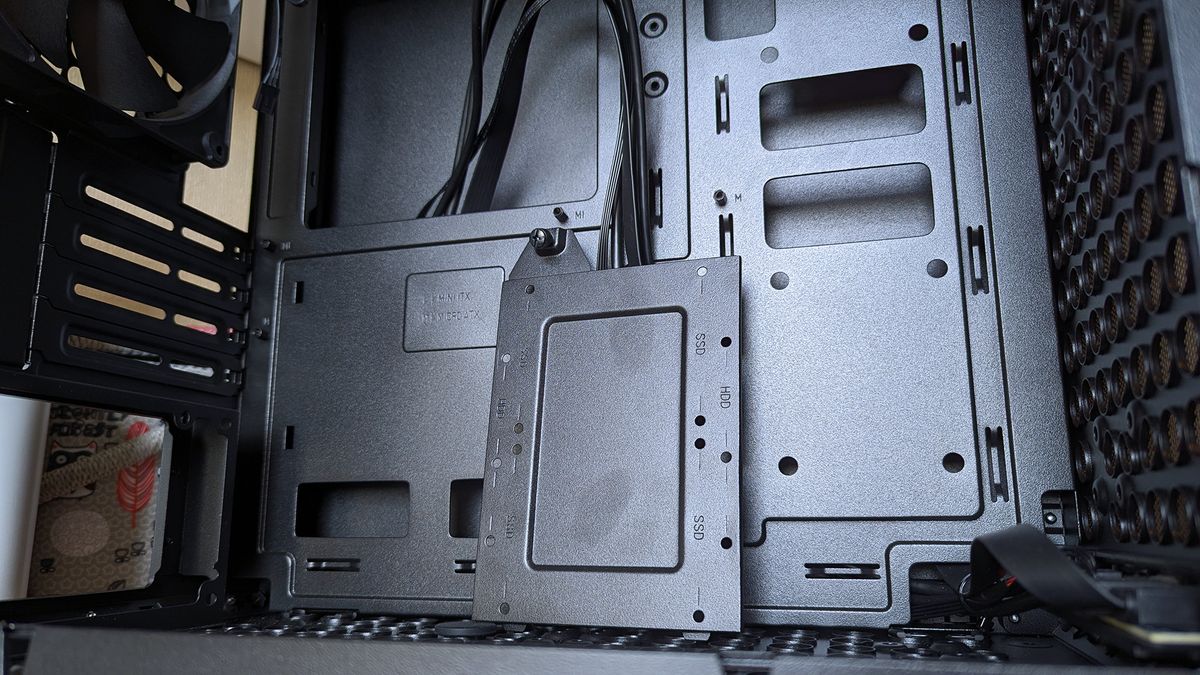 Cooler Master Qube 340 PC case internals showing motherboard tray with standoffs and a detached SSD mounting tray