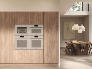 a bank of built in ovens in a beige color in wooden cabinetry