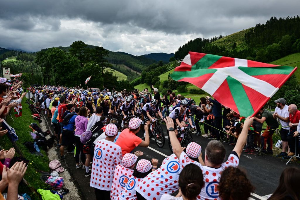 Spectators line the race route with Basque regional flags as the pack of riders cycles during the 2nd stage of the 110th edition of the Tour de France cycling race 2089 km between VitoriaGasteiz and San Sebastian in northern Spain on July 2 2023 Photo by Marco BERTORELLO AFP Photo by MARCO BERTORELLOAFP via Getty Images