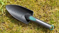 A black plastic garden hand trowel on a lawn