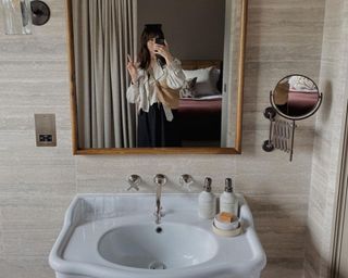 Woman in bathroom mirror with white sink