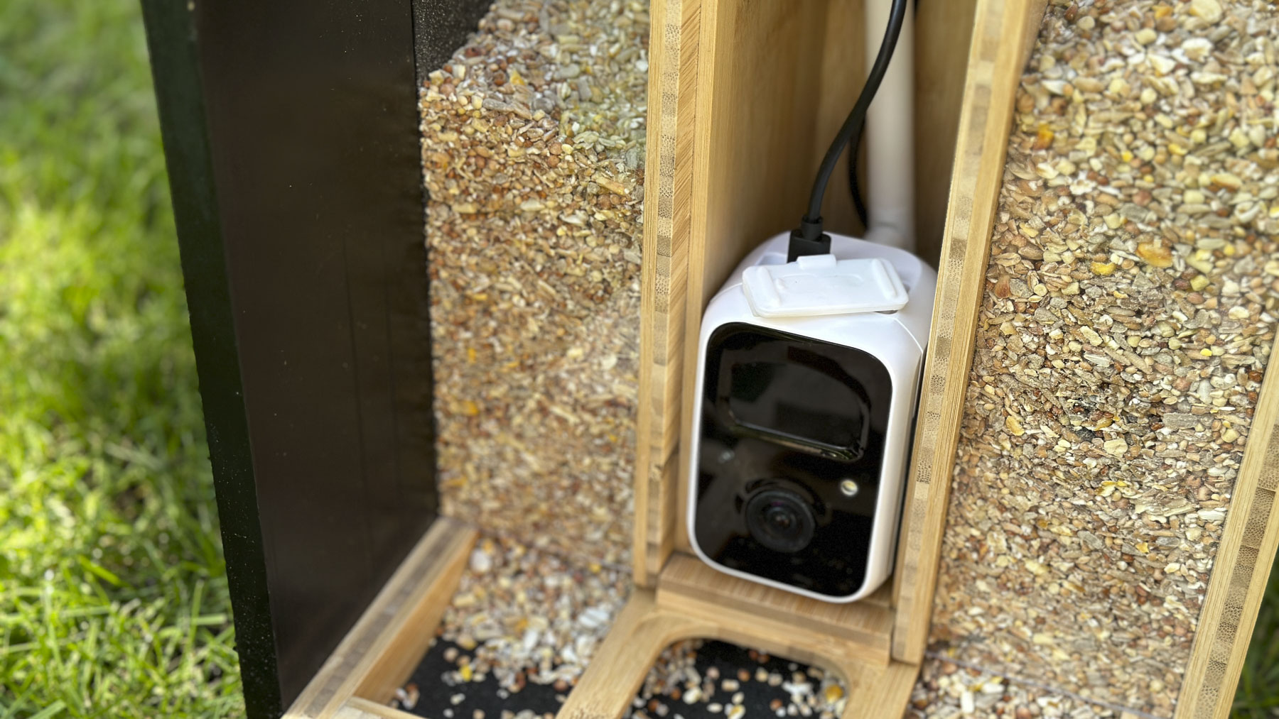 Netvue Birdfy Bamboo bird feeder camera outside on the grass and closeup of the camera unit