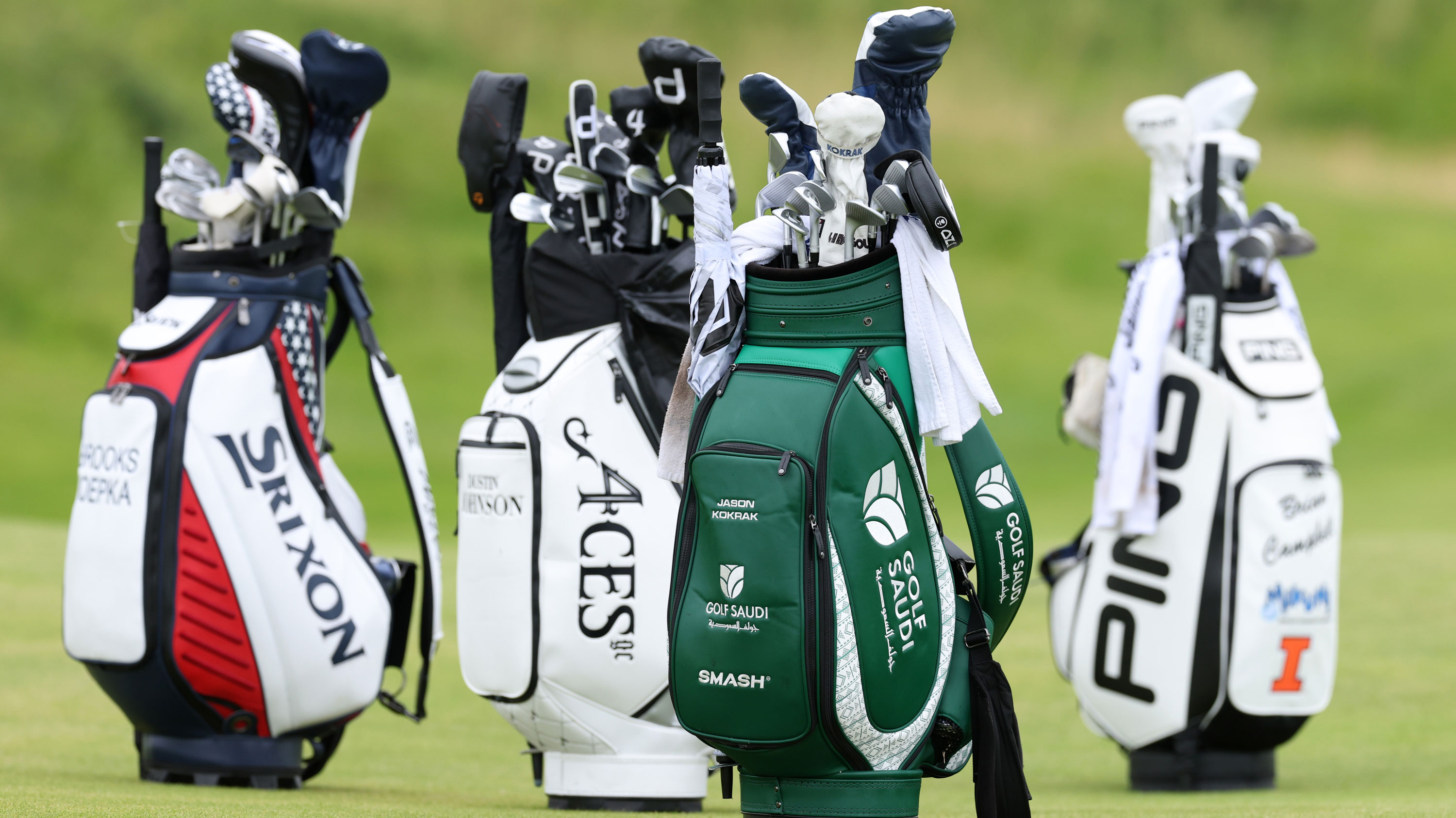 four golf bags standing up on a golf course