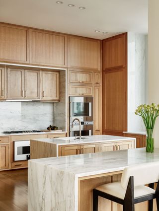 The kitchen in a NYC apartment renovation, featuring wooden cabinets and a marble-topped kitchen island