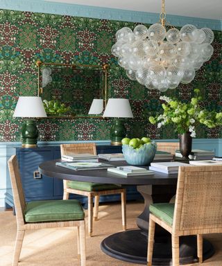 dining room with patterned green wallpaper and statement light fixture
