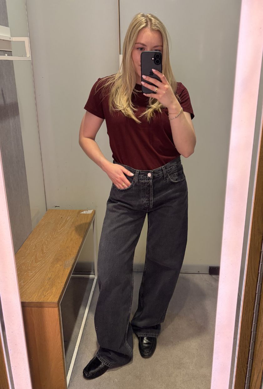 Woman wears burgundy top and black barrel-leg jeans