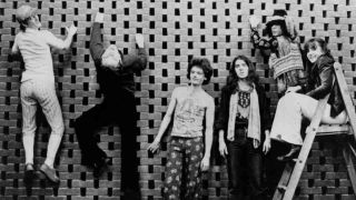 The members of Gong climbing a wall in the 1970s