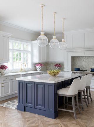 white traditional kitchen with blue island glass pendant lights and three white vases with blue spots and pink flowers