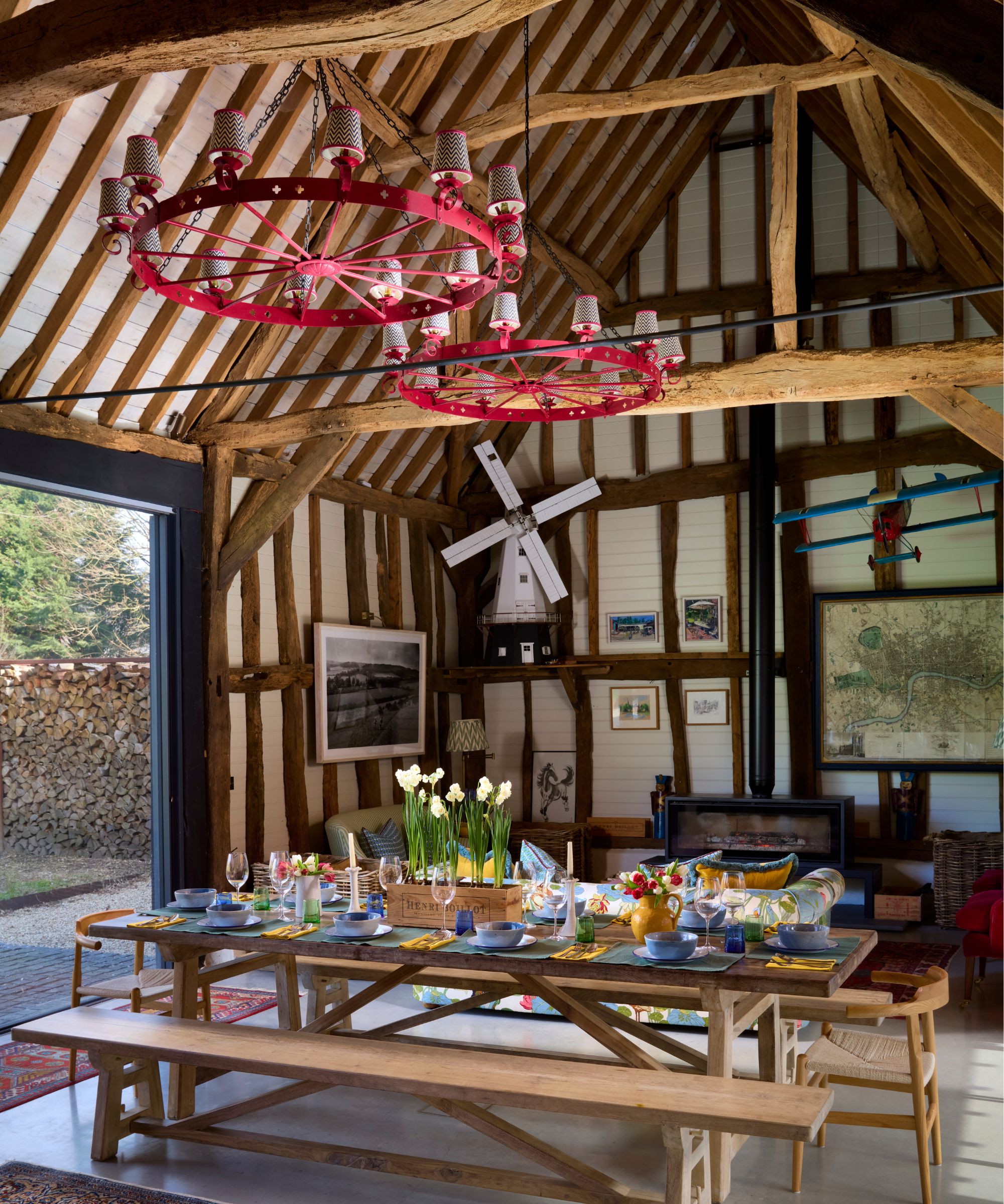 a rustic barn conversation with two red chandelier and a large wooden table