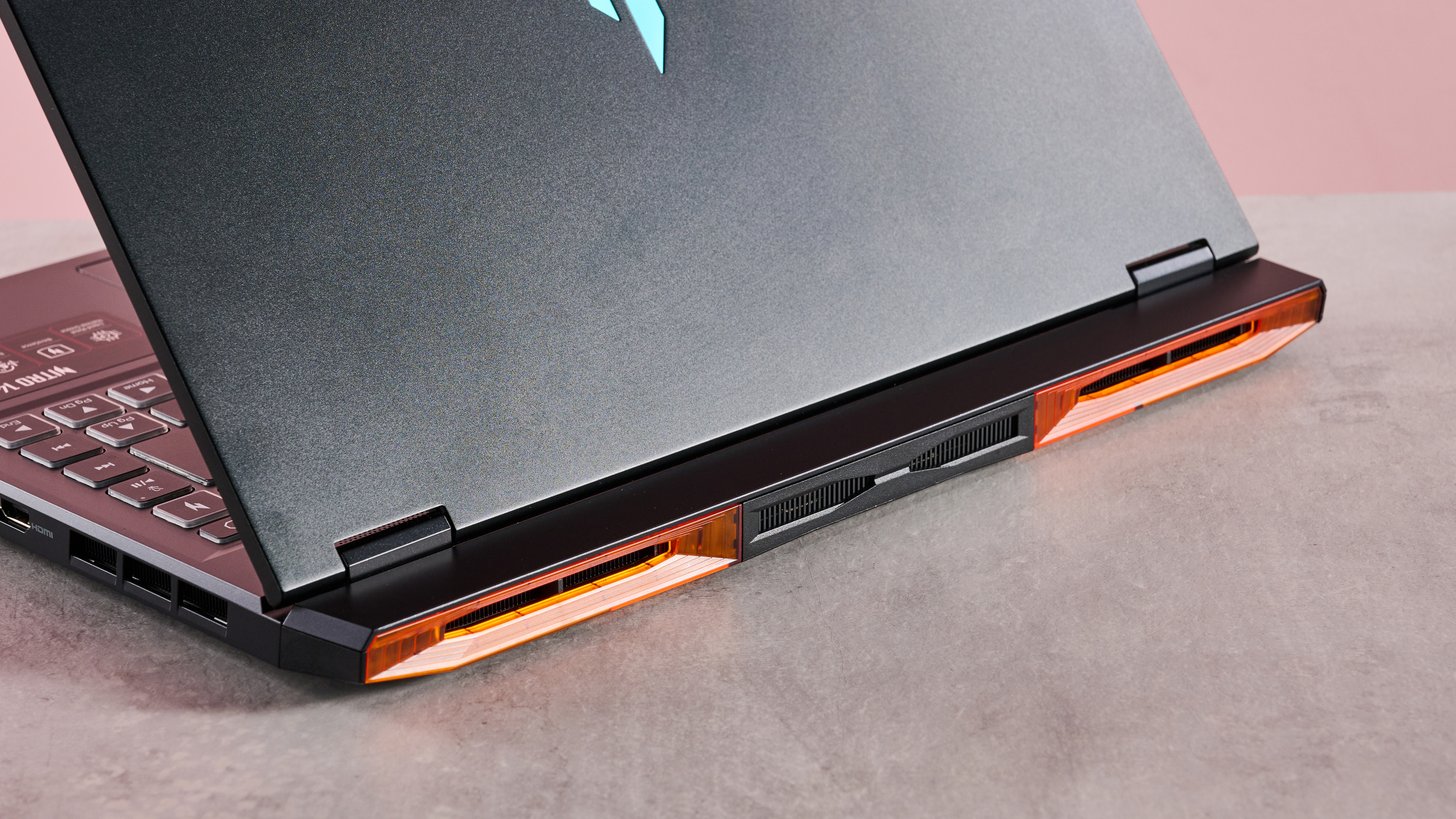 The Acer Nitro 14 compact gaming laptop photographed on a coral background.