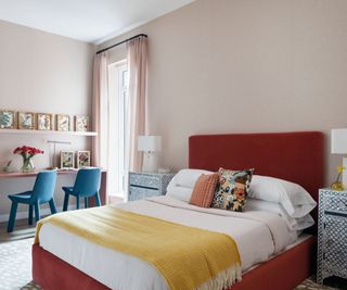Red bed, yellow blanket, blue chairs, pink walls