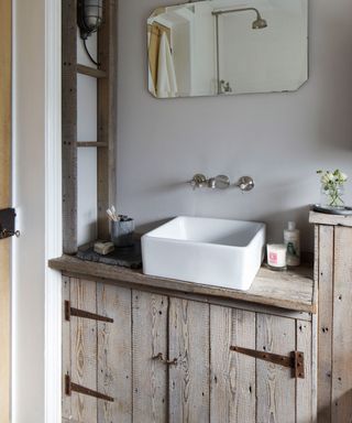 bathroom with pale grey walls and natural wooden textured cupboard