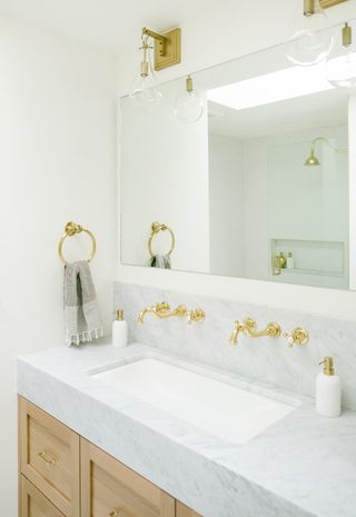 bathroom vanity with marble countertop and wooden base and gold hardware