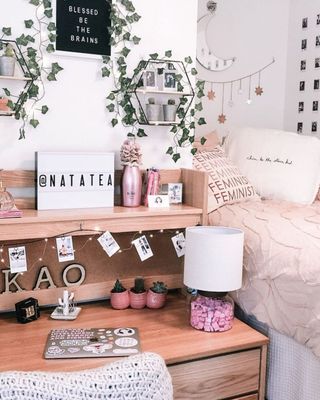 A pink dorm room with a decorated desk and bed