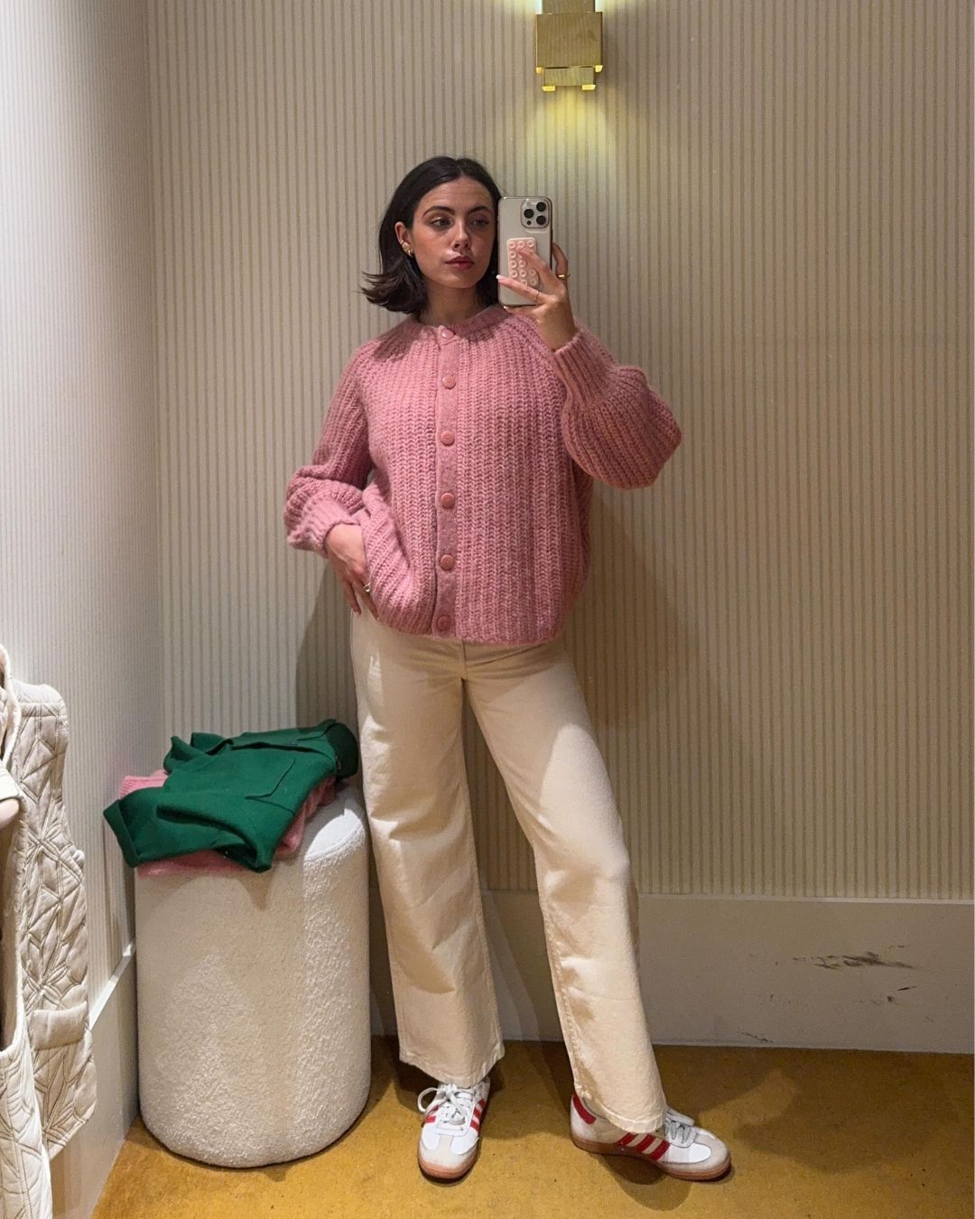 Influencer @tia_dewitt wears a pink jumper with cream jeans and white trainers.