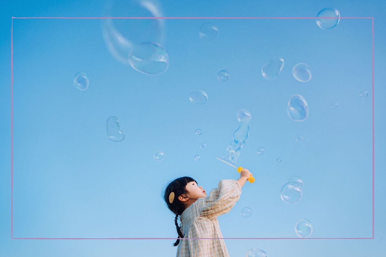 Inspirational quotes illustrated by girl with black hair blowing bubbles in big blue sky