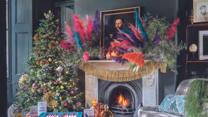 Living room with Christmas tree and brightly coloured dried flowers on mantlepiece.