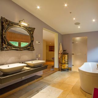 bathroom with bathtub and washbsin and oval mirror