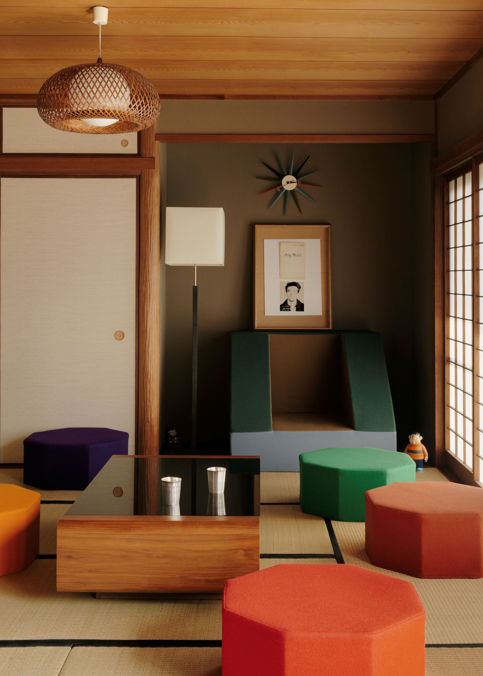 An abstract and colorful Japanese living room with angular yet inviting colorful stools and seating around a low profile coffee table with too cups on top and minimal decor in the space