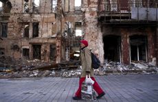 A woman walks past a destroyed building in Mariupol, Ukraine