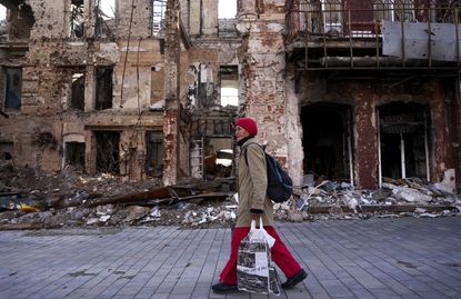 A woman walks past a destroyed building in Mariupol, Ukraine