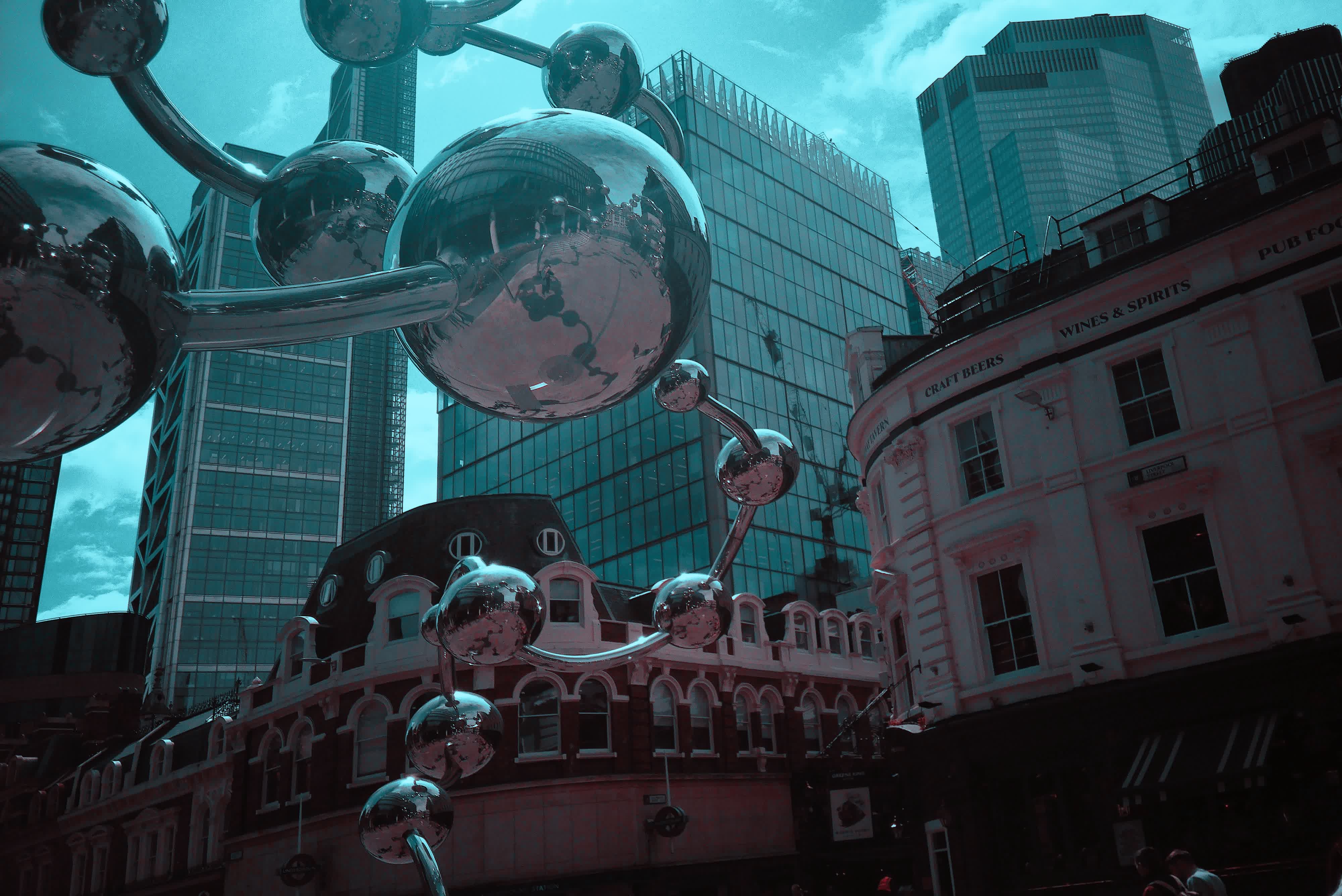Photograph taken with the RewindPix digital compact showing street sculpture of metal balls in front of tall buildings, in infrared style