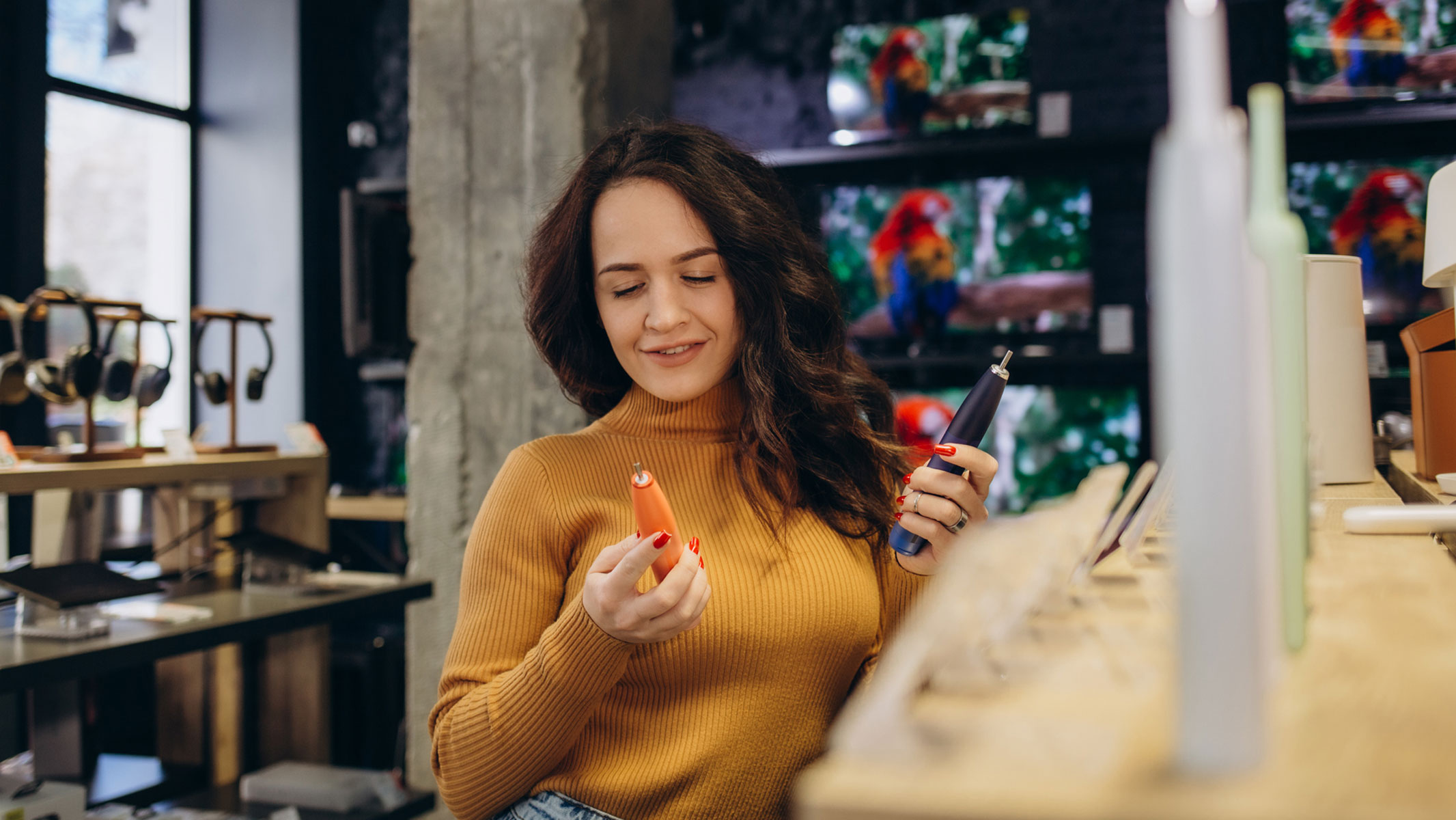 A picture of a young woman comparing two electric toothbrushes in a shopping store