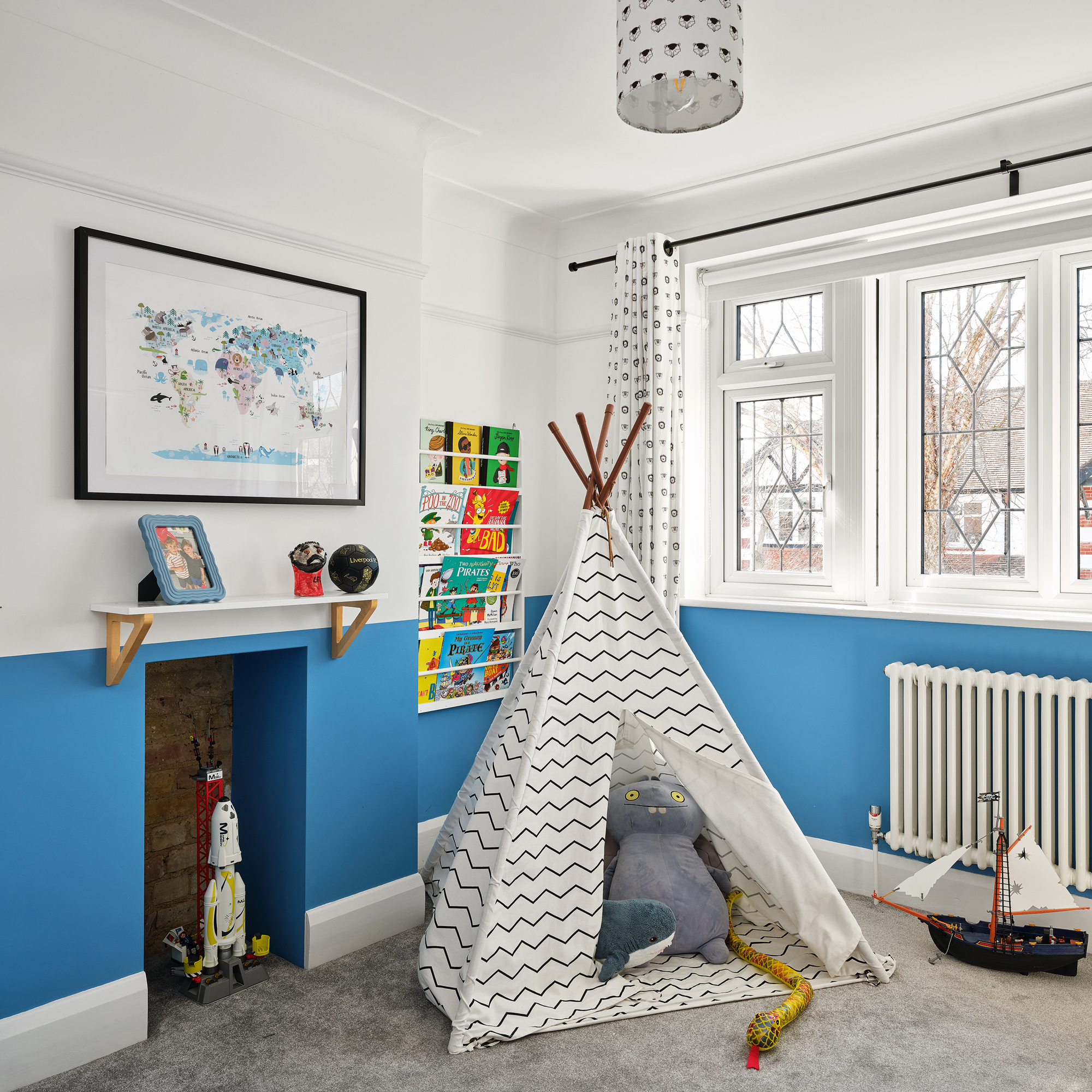 a child's room with blue and white walls, a teepee and a wall-hung bookshelf