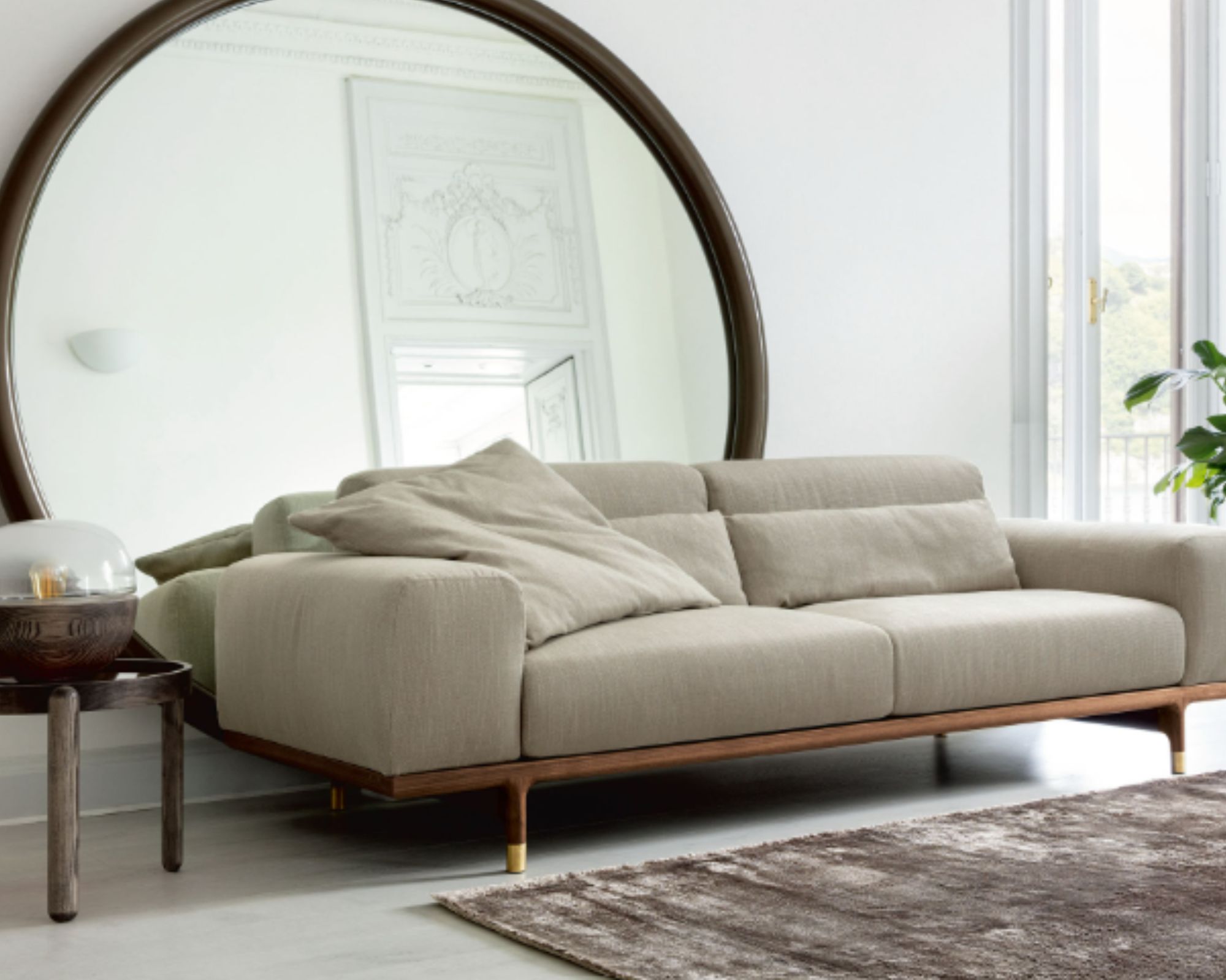 Neutral modern sofa with a large circular mirror behind