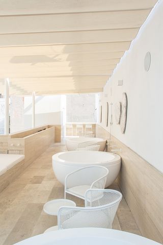 Outside seating area with single bathtubs, wooden flooring and white furniture