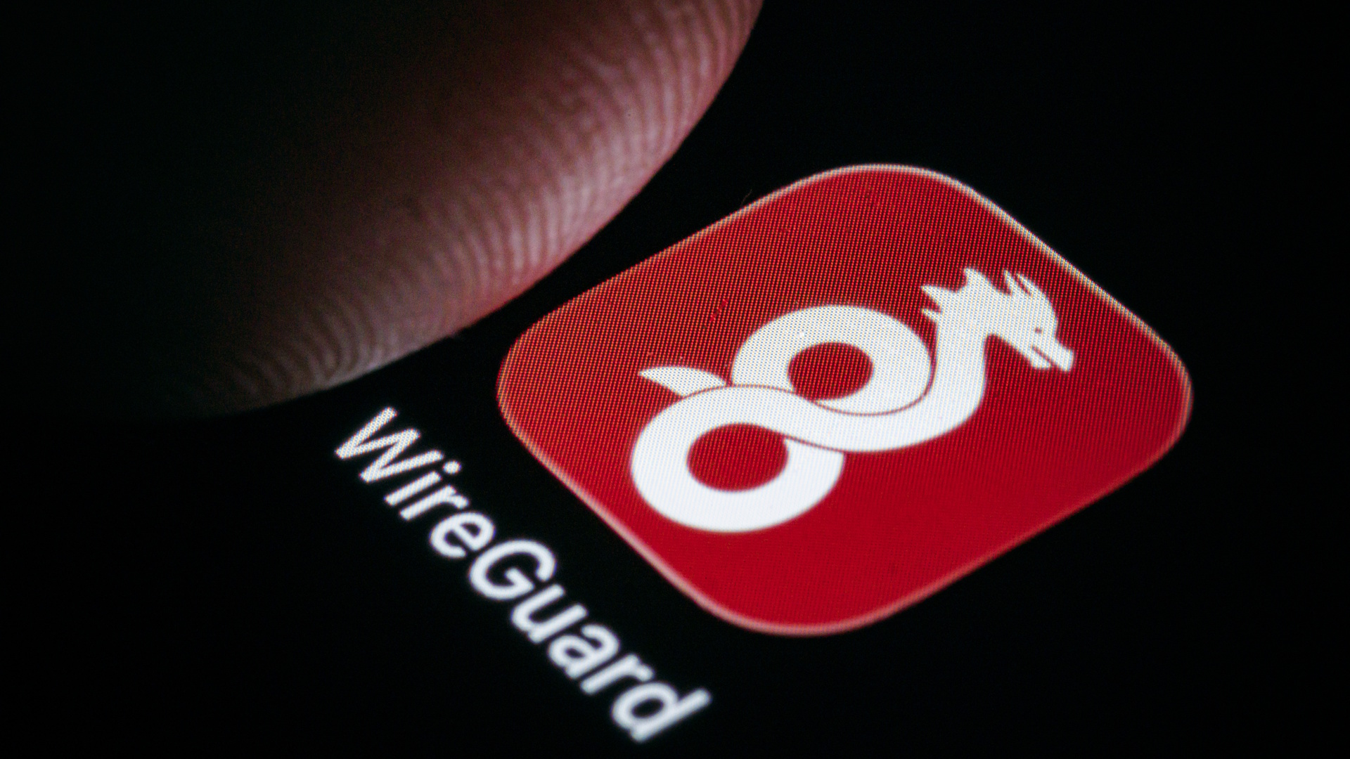 The WireGuard logo shown as an app on a smartphone next to a finger.