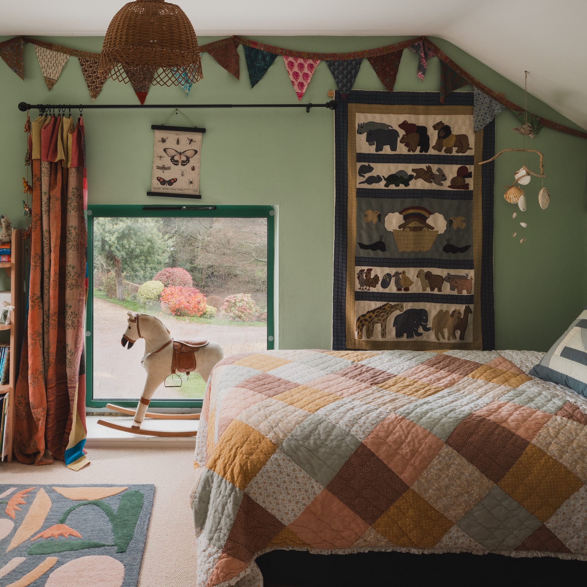 twin children&#039;s bedroom with green walls and single beds with patchwork quilts and bunting