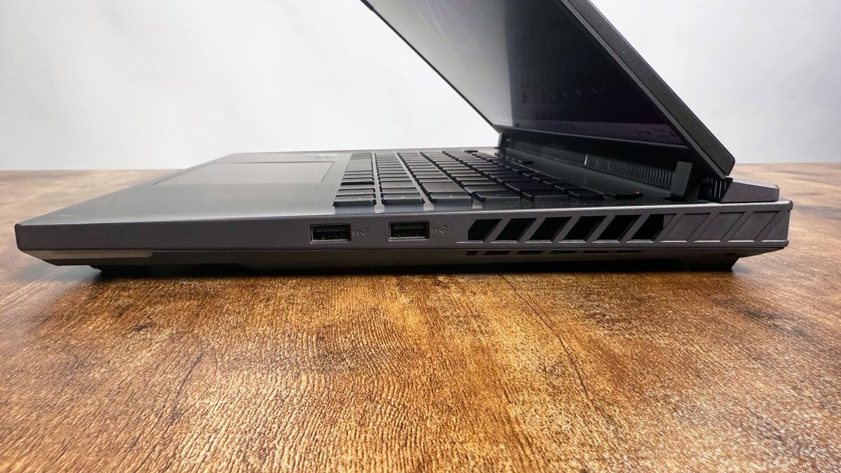 Close up of the right-side ports on the Asus ROG Strix G16 (G614FR) gaming laptop on a wooden desk against a gray background.